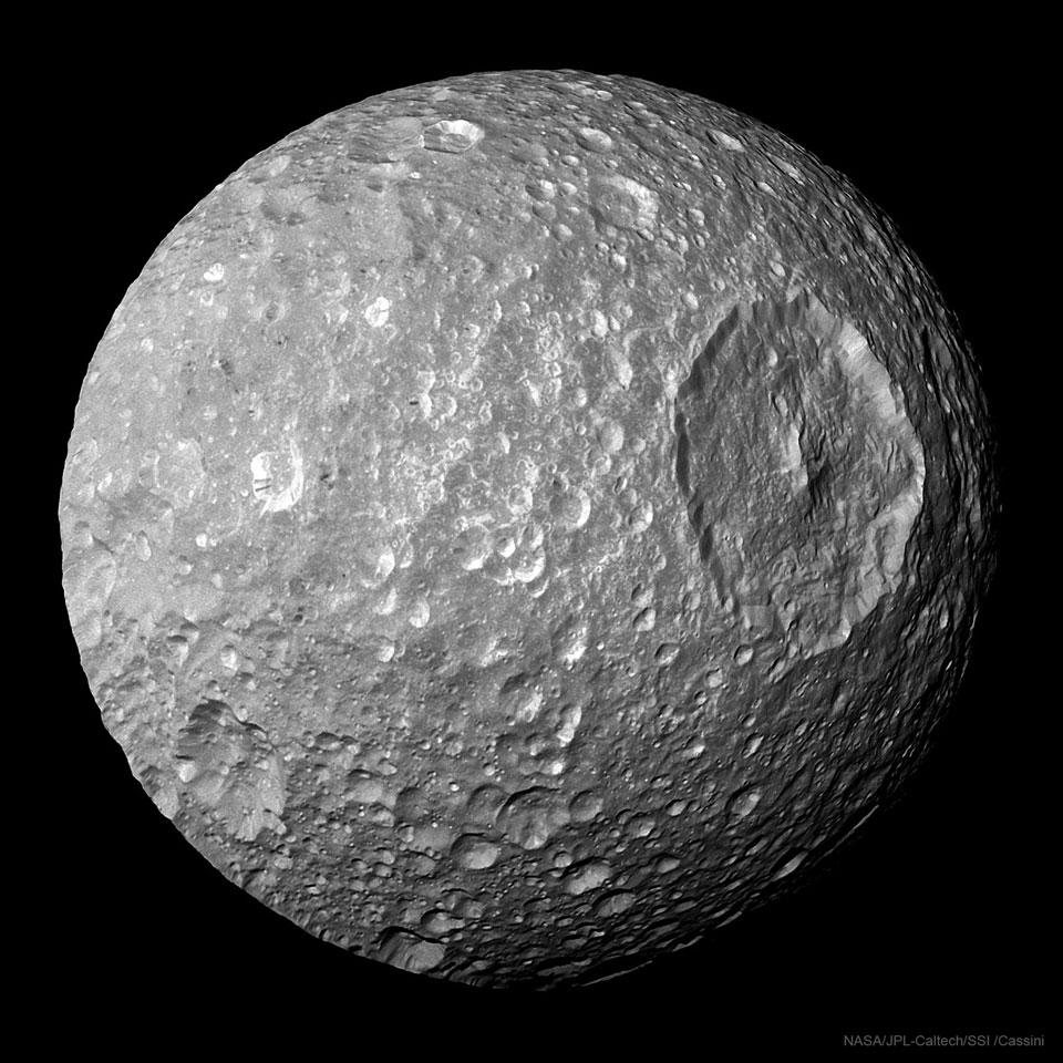 图为土星的卫星土卫一，有一个非常大的圆形陨石坑。有关更多详细信息，请参阅说明。