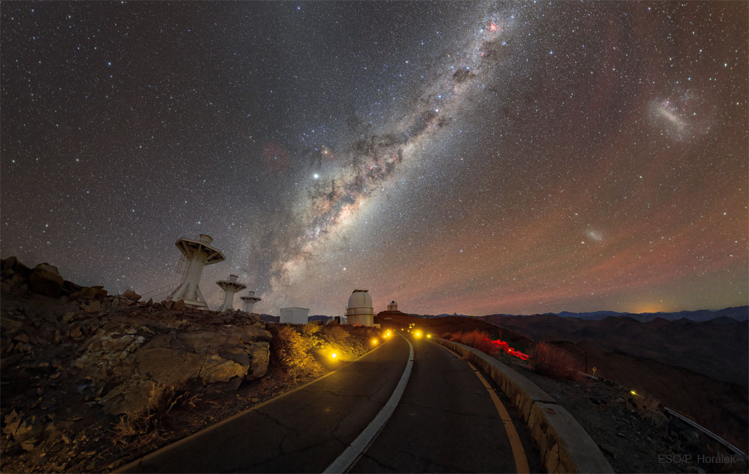通往智利拉西拉天文台的道路图像，望远镜在地平线上，恒星、星系、行星和天空中的气辉。请参阅说明以获取更多详细信息。