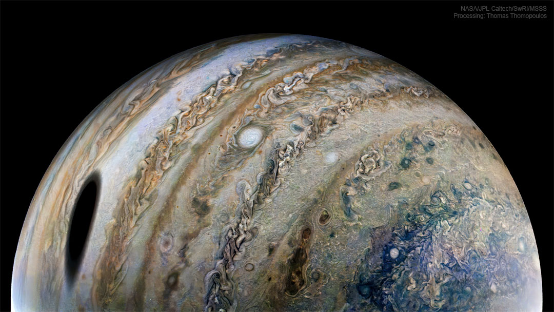特色图片显示了NASA经过的机器人宇宙飞船朱诺号看到的木星行星。在木星上看到的一个大黑点是木星卫星木卫一的阴影。请参阅说明以获取更多详细信息。