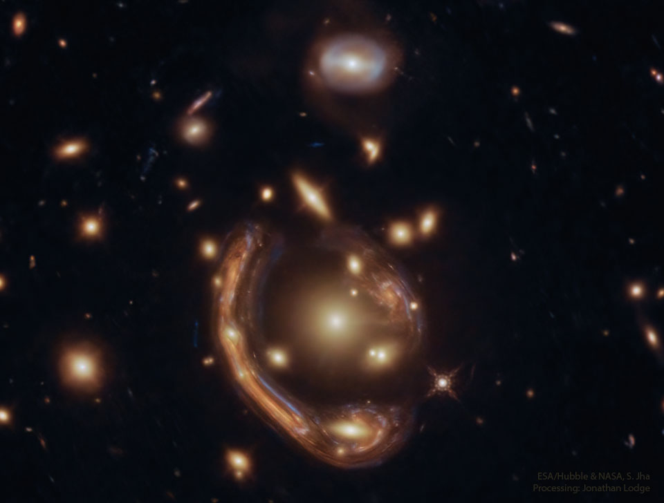 这张特色图片显示了一个遥远的星系被引力透镜扭曲成围绕星系团中心的巨大弧线。请参阅说明以获取更多详细信息。