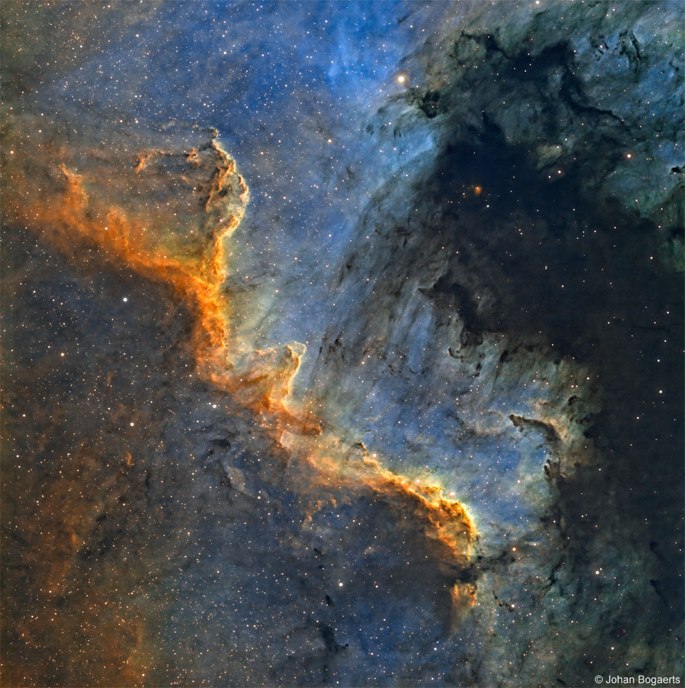 特色图像显示了天鹅座的恒星诞生之墙，一条锯齿状的明亮气体和暗尘埃设置在蓝色背景中，靠近非常黑暗的暗尘埃。请参阅说明以获取更多详细信息。