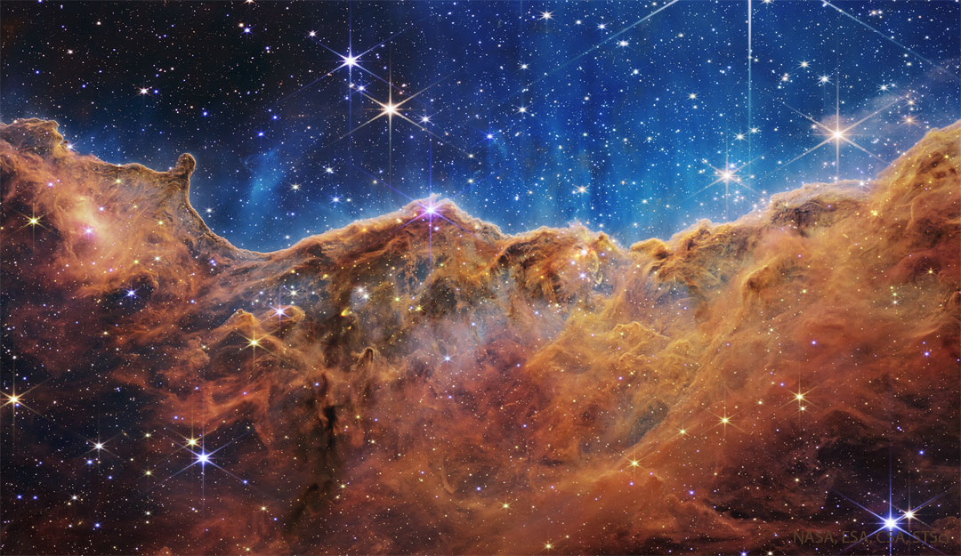 这张特色图片显示了韦伯太空望远镜拍摄的船底座星云中一条密集的黑色尘埃线，看起来就像悬崖。请参阅说明以获取更多详细信息。