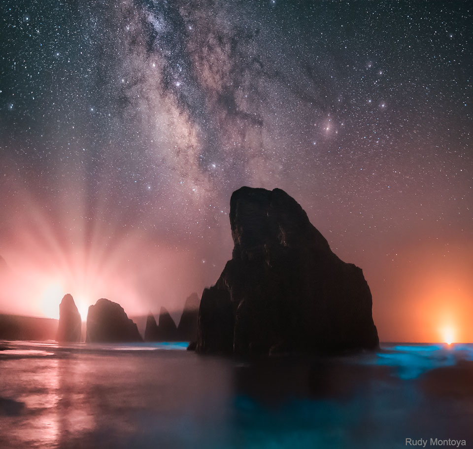 这张特色图片显示了美国俄勒冈州海岸的岩石露头，水中有蓝色的生物发光，我们银河系的中心带在天空中。请参阅说明以获取更多详细信息。
