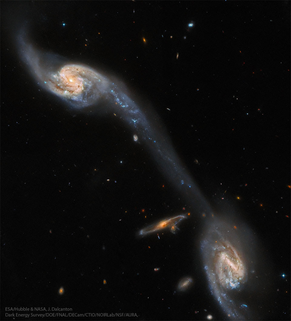 这张特色图片显示了几个相互作用的螺旋星系，其中有一座恒星和气体的桥梁连接着两个最亮的星系。有关更多详细信息，请参阅说明。