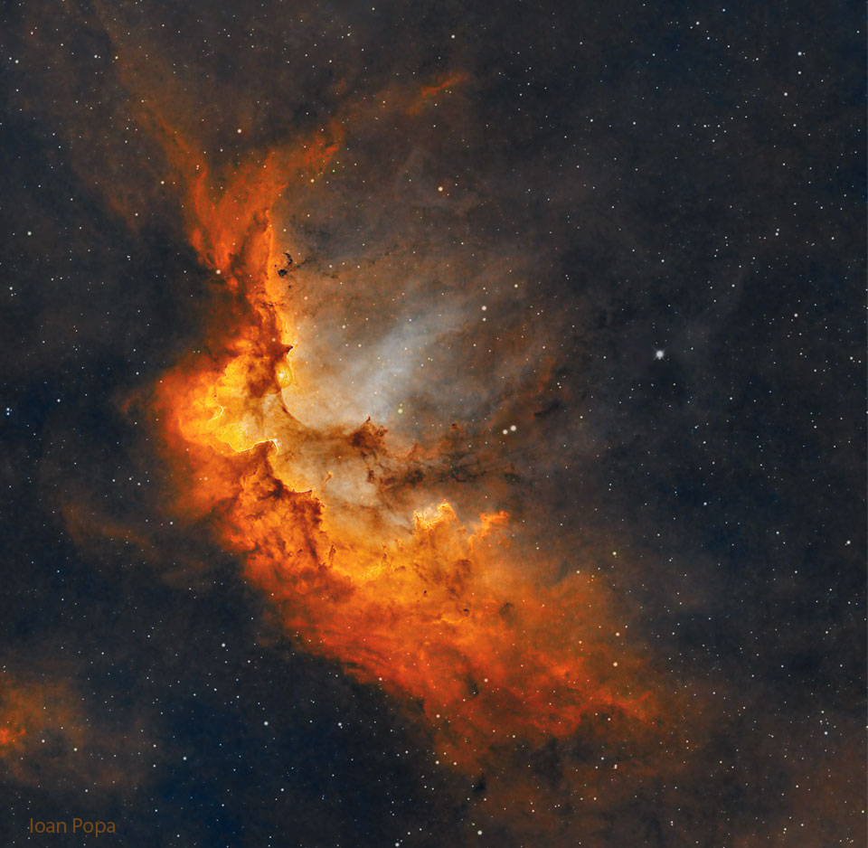 这张特色图片显示了一个红光闪烁的巫师星云，星光背景下有气体和尘埃柱。有关更多详细信息，请参阅说明。