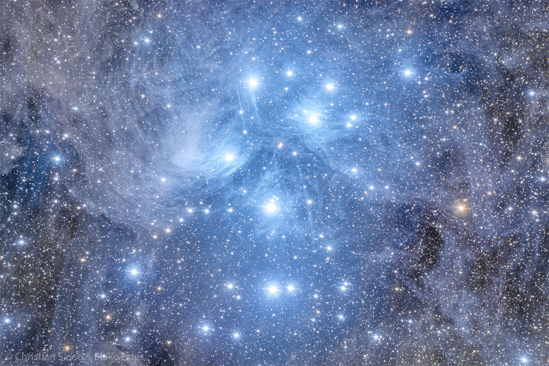 这张特色图片显示许多蓝色恒星聚集在蓝色发光的气体和尘埃中。请参阅说明以获取更多详细信息。
