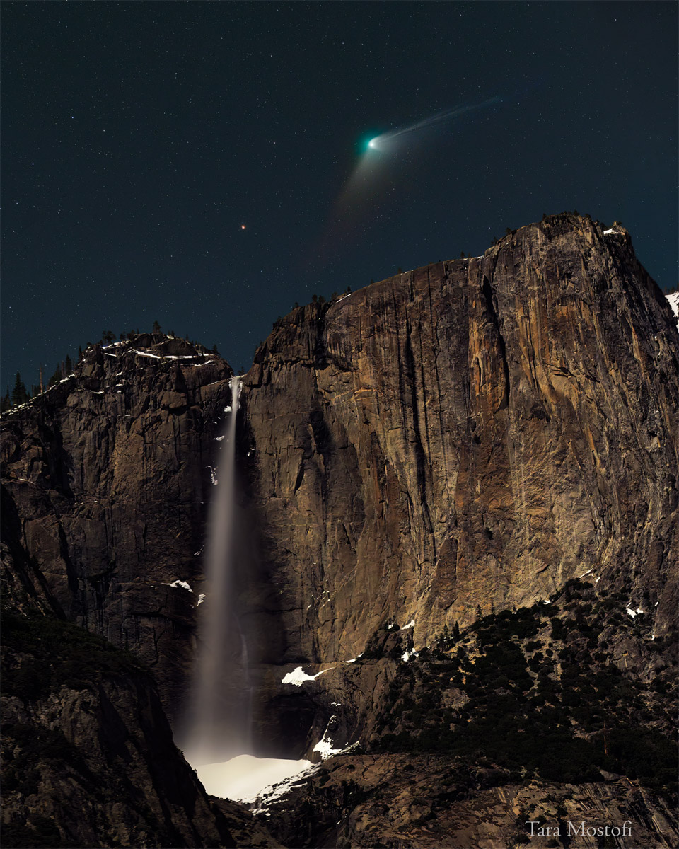 一颗头部呈绿色，尾部延伸的彗星出现在高水位的上方。在瀑布上方的夜空中，还可以看到橙红亮星——北极二。有关更多详细信息，请参阅说明。