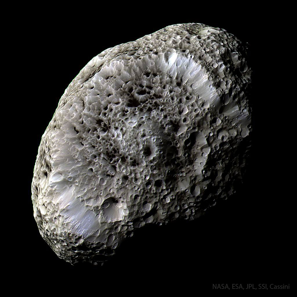 图中显示的是一个长方形的卫星，看起来像海绵一样，有许多奇怪的陨石坑。近距离观察表明，这些陨石坑的底部覆盖着一种黑色物质。有关更多详细信息，请参阅说明。