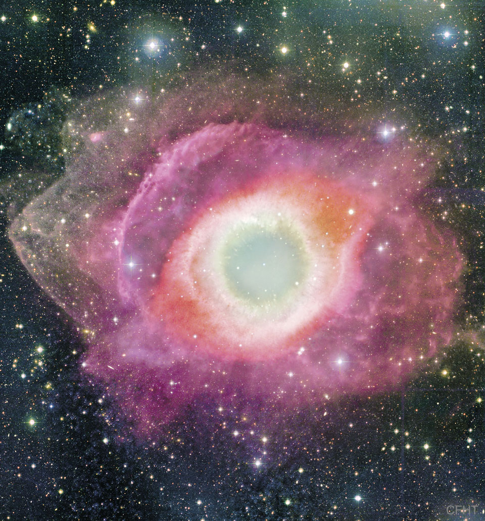 图中显示了一个彩色的圆形星云，它的中心为米色，更远的地方为红色，更远的地方是气体紫色的环。有关更多详细信息，请参阅说明。