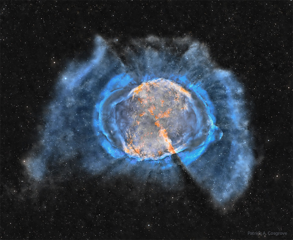 膨胀的星际气体云显示为内部橙色和外部蓝色细丝。在黑暗的背景中可以看到许多恒星。有关更多详细信息，请参阅说明。