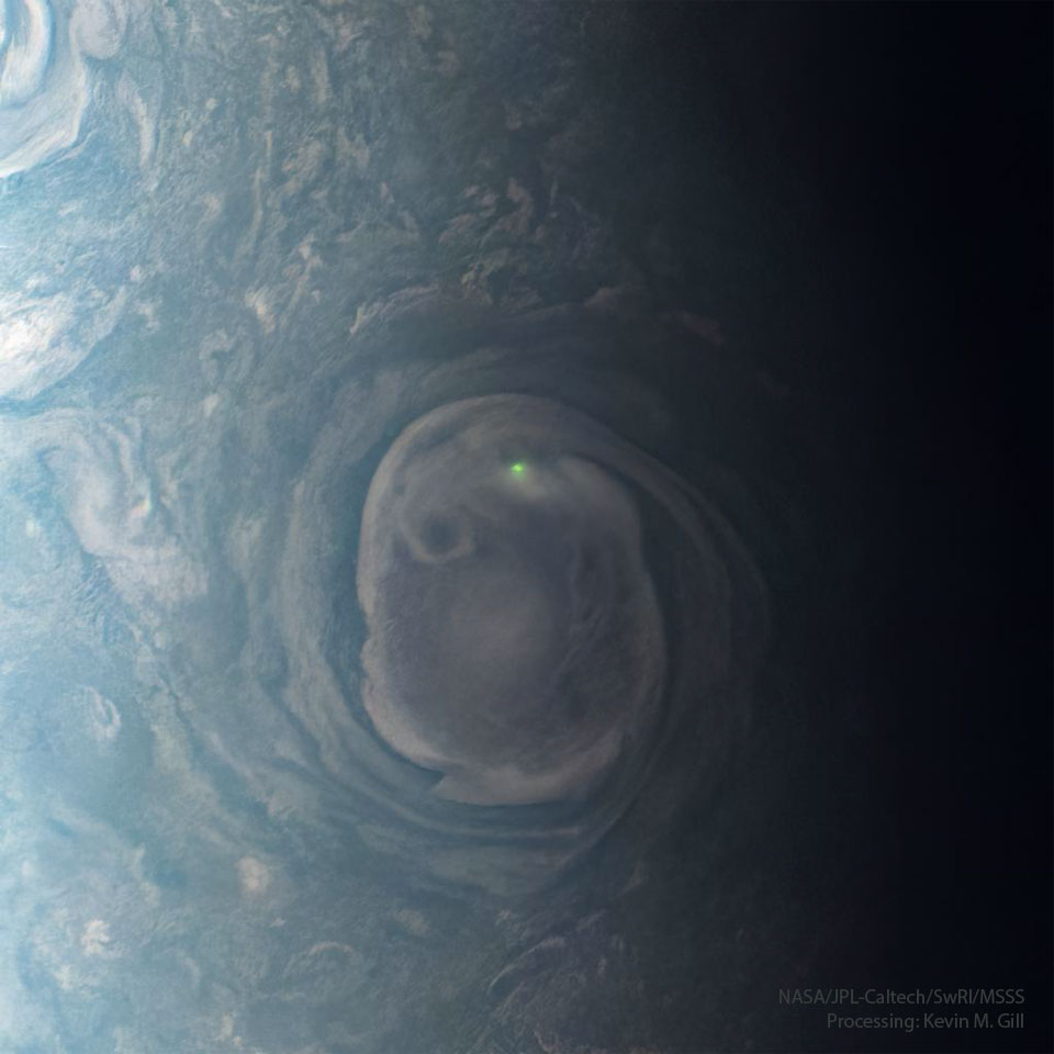 木星上一个巨大的漩涡云在其顶部附近有一个明亮的绿色斑点。云层被木星高层大气中其他不太引人注意的部分所包围。有关更多详细信息，请参阅说明。