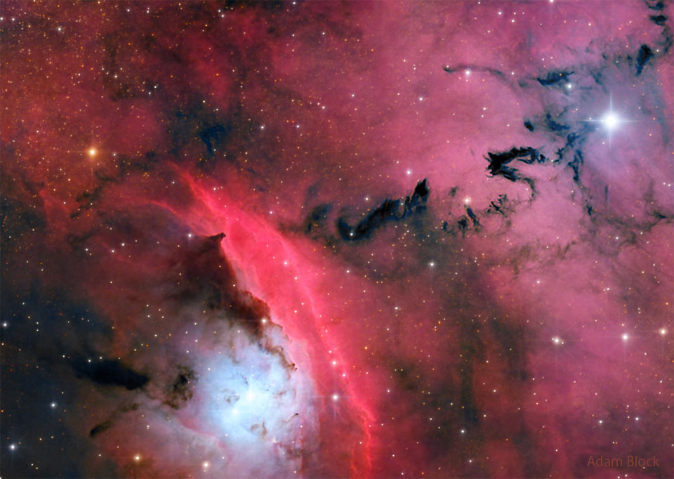 一个繁忙的恒星形成区域被红色发光的云和黑暗的不祥形状的尘埃所突出显示。有关更多详细信息，请参阅说明。