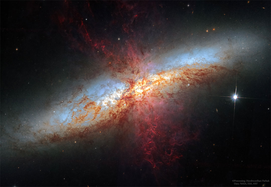 螺旋星系有许多复杂的红色细丝延伸出来。有关更多详细信息，请参见说明。
