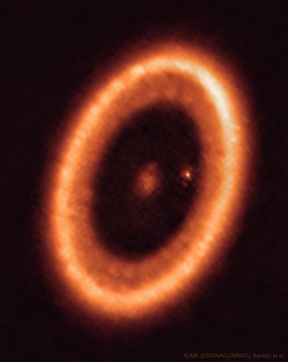 显示了一个橙色的椭圆环，它是恒星PDS 70周围的气体和尘埃碟。在尘埃碟的中心是一个模糊点，在尘埃碟的右内边缘附近是另一个模糊点。有关更多详细信息，请参阅说明。