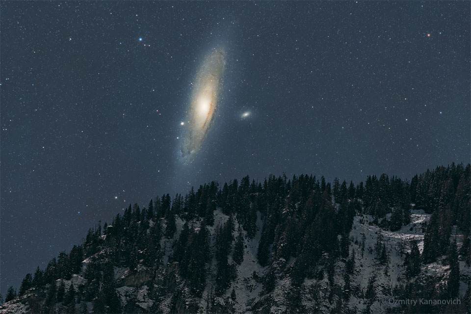 图中是一座雪山上的夜空，黑暗的天空被一个巨大的螺旋星系——仙女座星系所占据。有关更多详细信息，请参阅说明。