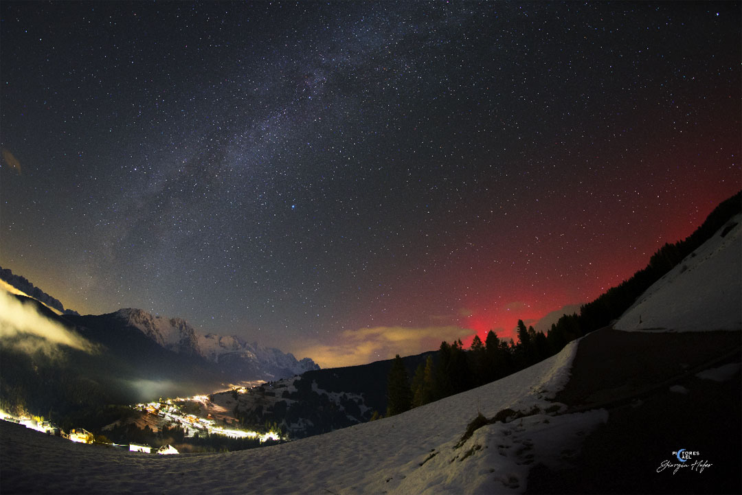 山谷上方的夜空显示了银河系的中央盘面从左下方穿过的完整画面。在照片的右边，山那边的发出一种不同寻常的红光: 极光。有关更多详细信息，请参阅说明。