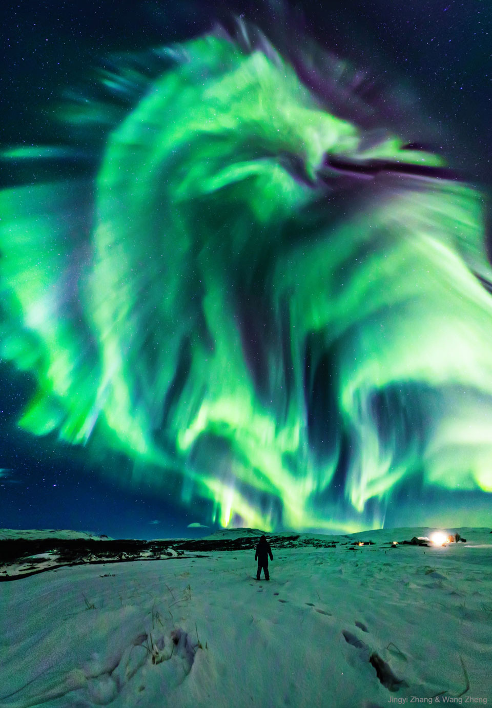 一个人站在雪地上，仰望星空。天空中，出现了一大片绿色极光，形似巨龙。有关更多详细信息，请参阅说明。