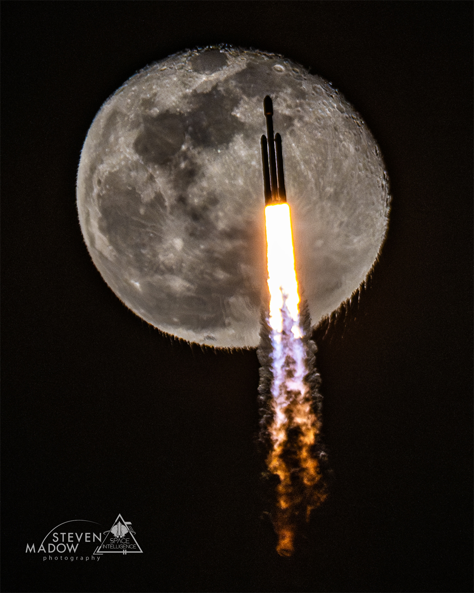 一枚火箭在发射过程中上升。它后面是一轮接近满月的月亮。火箭尾气本身是可见的，它使得月球底部呈现出不寻常的波纹。有关更多详细信息，请参阅说明。