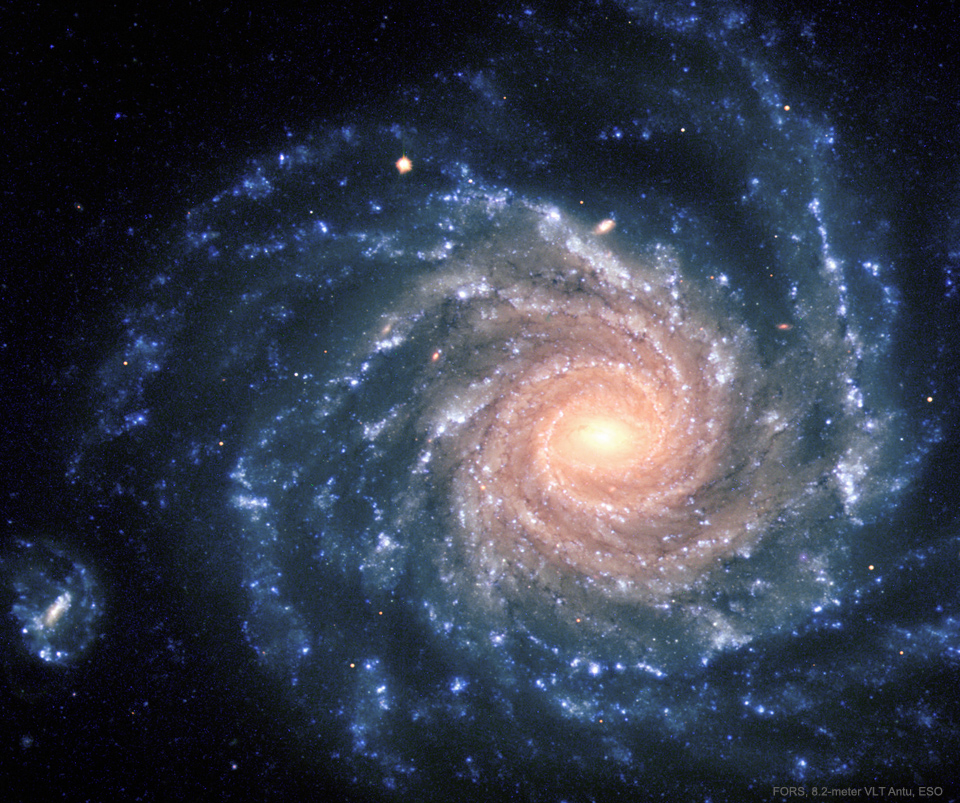 一个有着蓝色大旋臂的螺旋星系，其中心看起来更黄。有关更多详细信息，请参阅说明。