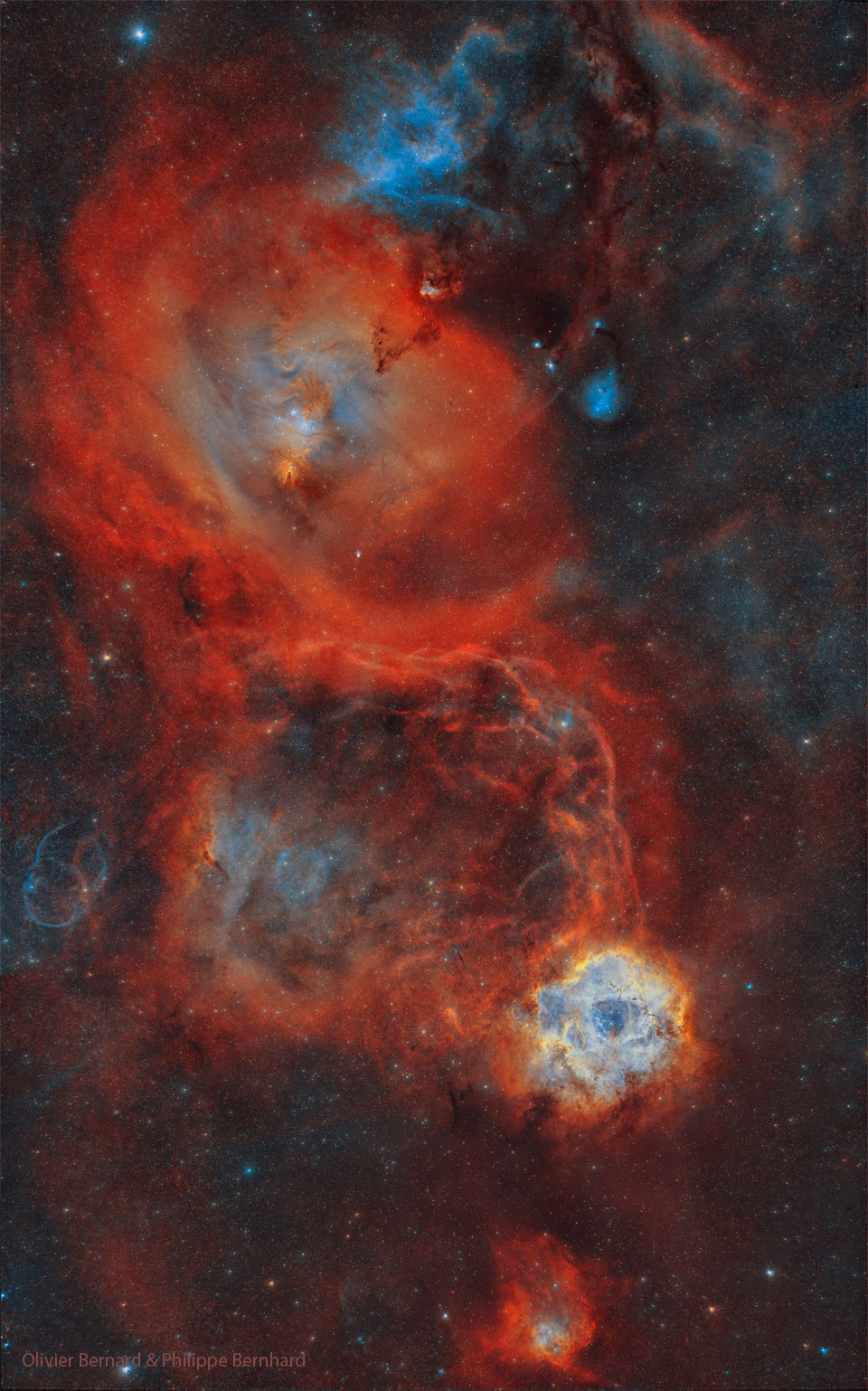 一个繁忙的恒星场显示了几个大的红色星云。玫瑰星云就在其中，在右下方可以看到，而圆锥形星云周围的星云更大，在左上方可以看到。有关更多详细信息，请参阅说明。