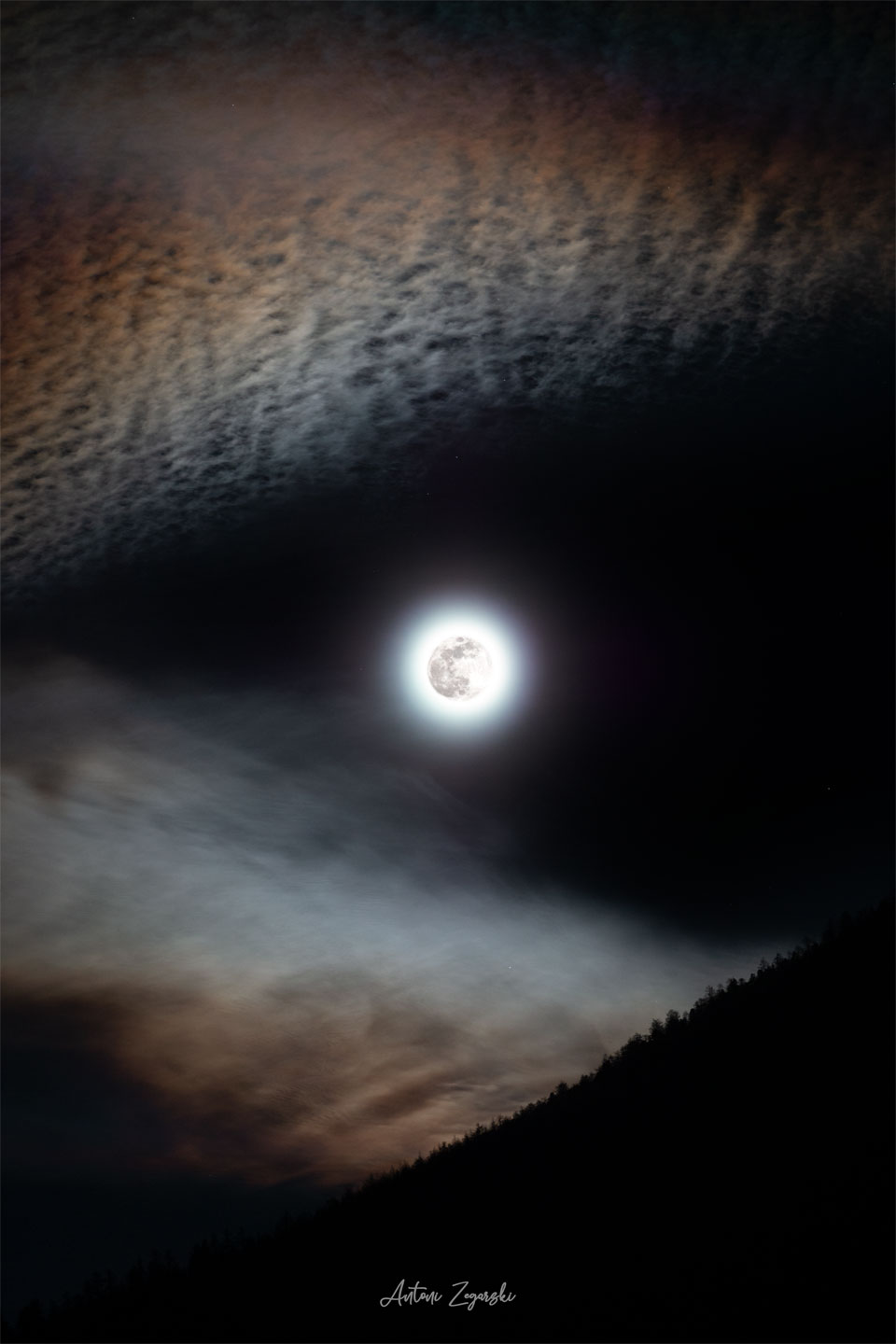 图像中央可以看到一轮明亮的满月。边缘处可见有角的云，使月亮看起来像是在狼的嘴里或狼的眼睛里。有关更多详细信息，请参阅说明。