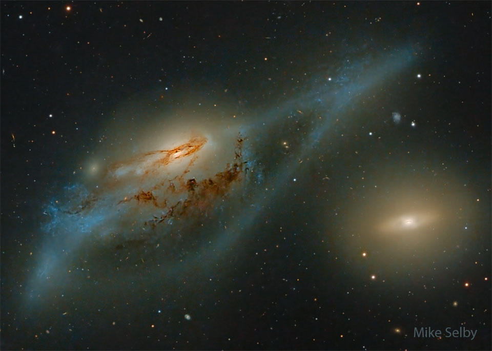 图为两个大星系。左边是一个扭曲的螺旋星系，而右边是一个相对没有特征的黄色盘状星系。在某些人看来，这些星系合在一起就像一双眼睛。有关更多详细信息，请参阅说明。